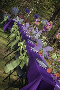 a long table with purple and green cloths on it is set up for an outdoor event