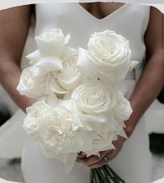 a bride holding a bouquet of white roses