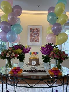 a table topped with lots of balloons and flowers next to a cake on top of a plate