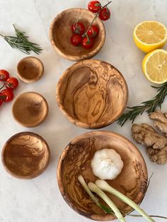 bowls and spoons with vegetables in them on a marble countertop next to lemon slices, tomatoes, garlic, and cherry tomatoes