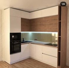 an empty kitchen with white cabinets and wood flooring on the walls, along with a black stove top oven