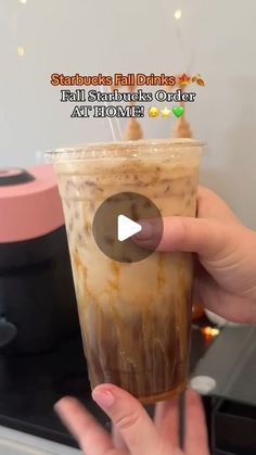 someone is holding up a drink in front of a stove top with the words starbucks's fall drinks on it