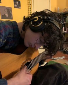 a person with headphones on laying down and holding a guitar in front of their face