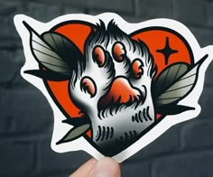 a hand holding up a sticker with an image of a cat's face