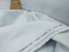 a white blanket with blue trim on it and a tag hanging from the top of it