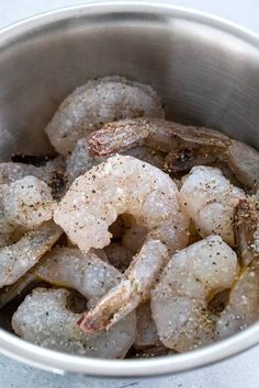 a silver bowl filled with shrimp on top of a table