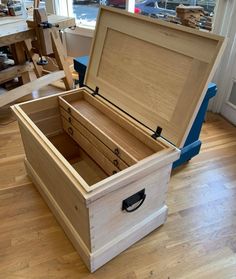 an open wooden box sitting on top of a hard wood floor next to a window