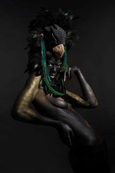 a woman with black and gold paint on her face, body and headdress