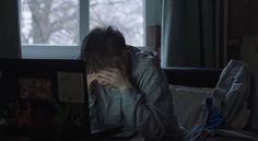 a person sitting on a couch in front of a laptop computer with their hands covering their face