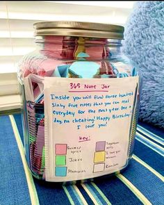 a jar filled with lots of different items on top of a blue table cloth next to a window