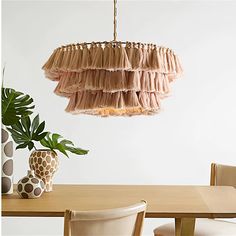 a wooden table topped with a vase filled with flowers next to a hanging light fixture