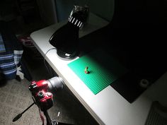 a camera is sitting next to a desk with a lamp on it and a lego figure in the background