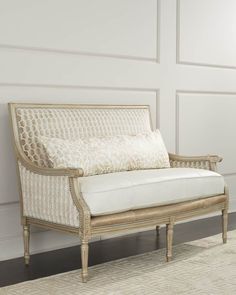 a white couch sitting on top of a rug in front of a wall with windows