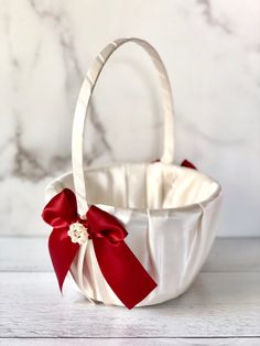 a white basket with a red bow on the front and side, sitting on a table