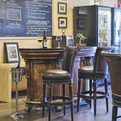 a bar with stools and a chalkboard on the wall in front of it