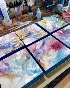 four square pieces of glass sitting on top of a wooden table next to other items