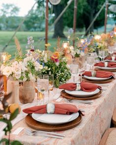 a long table set with place settings and flowers