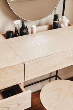 a wooden vanity with drawers and a round mirror