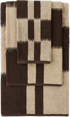 three brown and white towels folded on top of each other, one with a checkerboard pattern