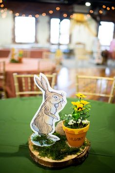 a table topped with a potted plant next to a cut out of a rabbit