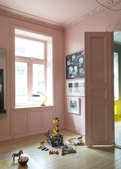 a room with pink walls and toys on the floor