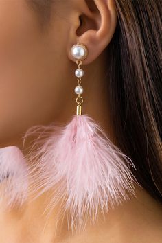 a close up of a woman wearing earrings with feathers and pearls on the back of her ear