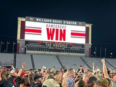 a crowd of people standing in front of a large scoreboard with the words gamecocks win on it