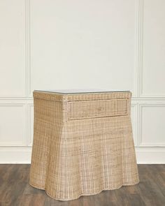 a wicker table with a glass top on wooden floor in front of white wall