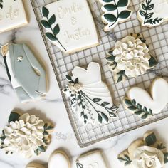 cookies decorated with flowers and leaves sit on a cooling rack next to the cookie cutters