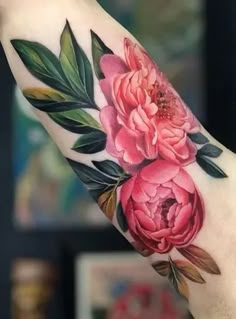 a woman's arm with flowers and leaves on it