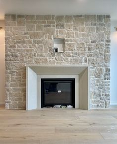 an empty room with a stone fireplace and wood floors