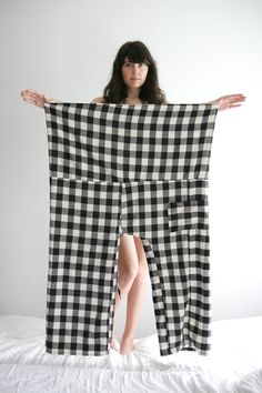 a woman standing on top of a bed holding a black and white checkered blanket