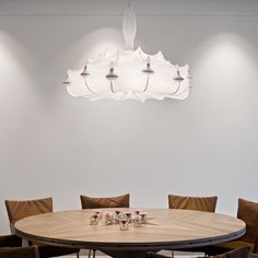 a round wooden table with six chairs around it and a chandelier hanging from the ceiling