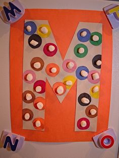 the letter m is made out of paper and decorated with different colored candies, including marshmallows