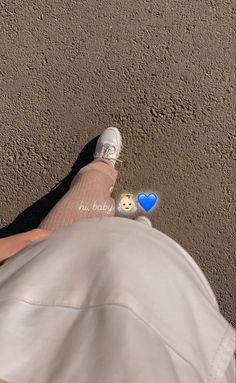 the person is wearing white shoes and has a blue heart on their left foot,