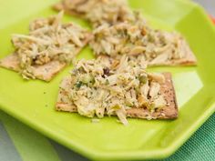 a green plate topped with crackers covered in toppings