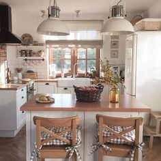 a kitchen with two wooden chairs sitting at the island