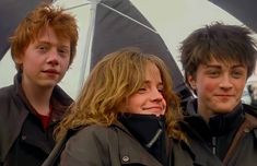 three people standing under an umbrella in the rain