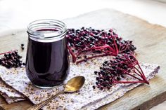 a glass jar filled with liquid sitting on top of a table next to some berries