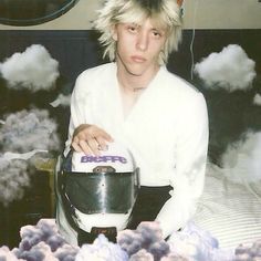 a man sitting on top of a bed with a motorcycle helmet in front of him