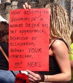 a woman holding a red sign that says your ability to defamaise a woman