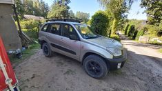 a small car parked on the side of a dirt road next to a red sign