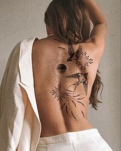 the back of a woman's body with tattoos on it