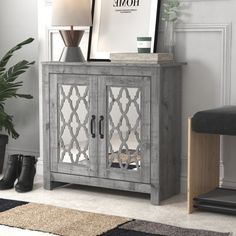 a grey cabinet with mirrored doors and a black footstool in front of it