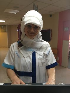 a woman in scrubs and bandages on her head is standing behind a metal table