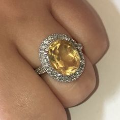 a woman's hand with a yellow and white diamond ring on top of it