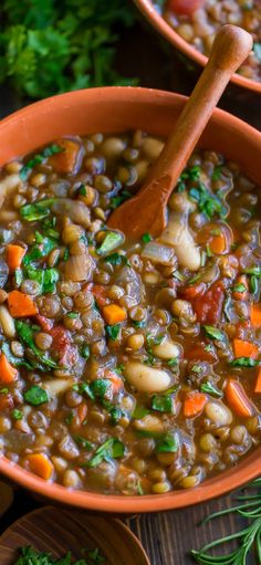 two bowls filled with lentils and carrots on top of a wooden cutting board