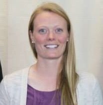 a woman with long blonde hair wearing a purple shirt and white blazer smiling at the camera