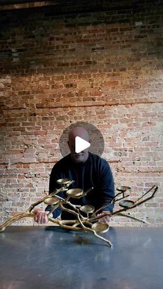 a man sitting at a table working on a piece of art that looks like branches