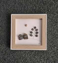 a shadow frame with rocks and houses in it on the floor next to a gray carpet